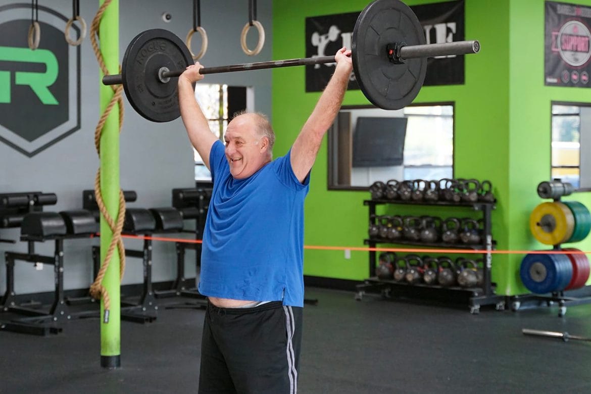Active older man lifting barbell overhead