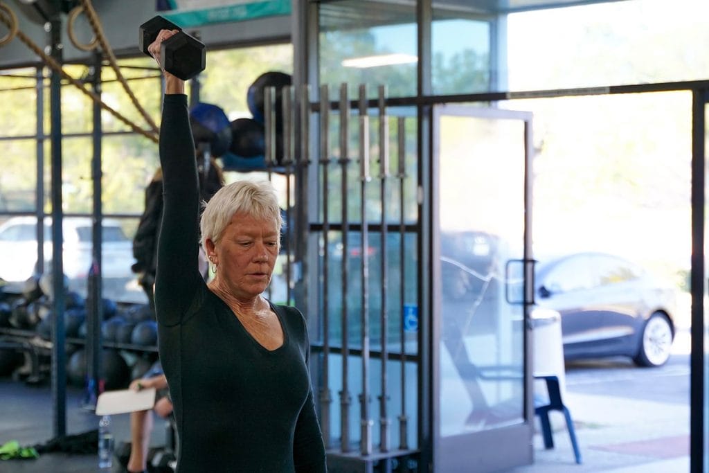 Active older woman lifting a dumbbell overhead