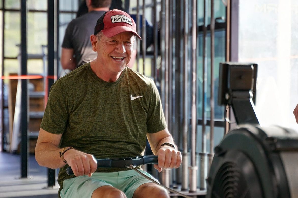 Active older man on a rowing machine smiling